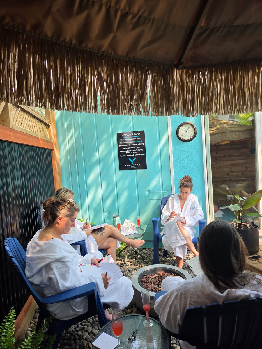Guests in plush robes journaling together around the outdoor fire pit at Contrast by Raven